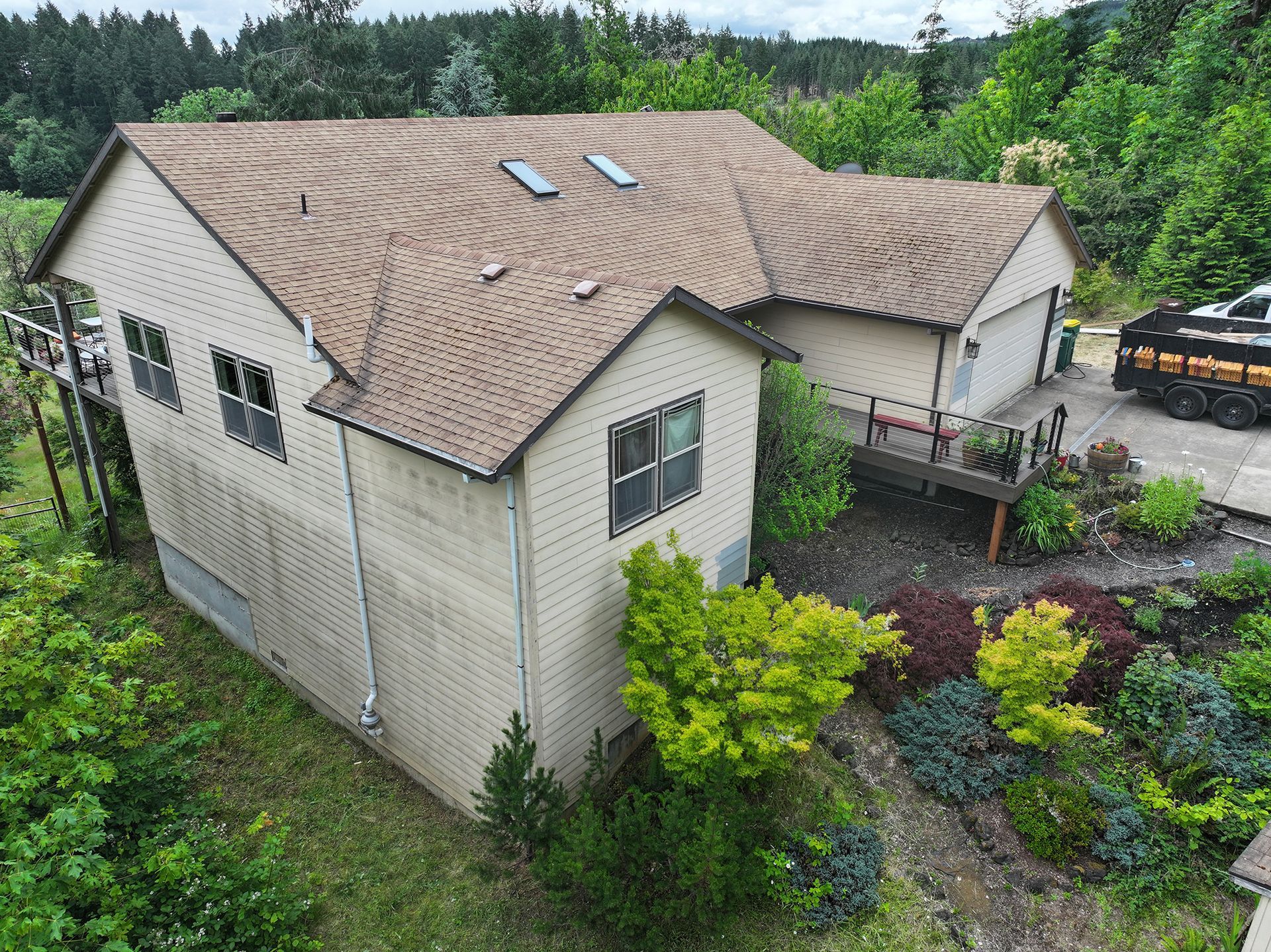 An aerial view of a house with a brown roof surrounded by trees.