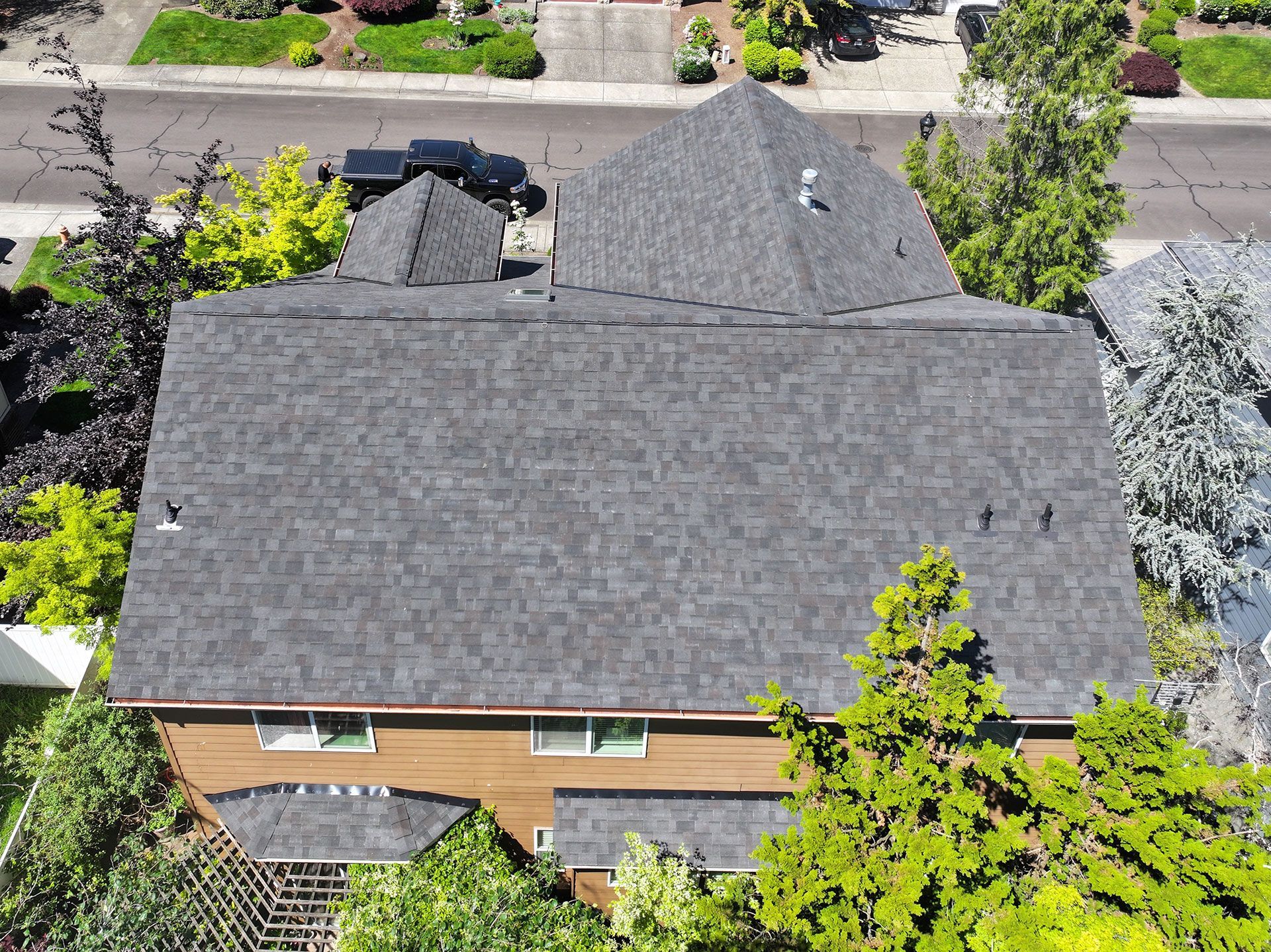 An aerial view of a house with a black roof surrounded by trees
