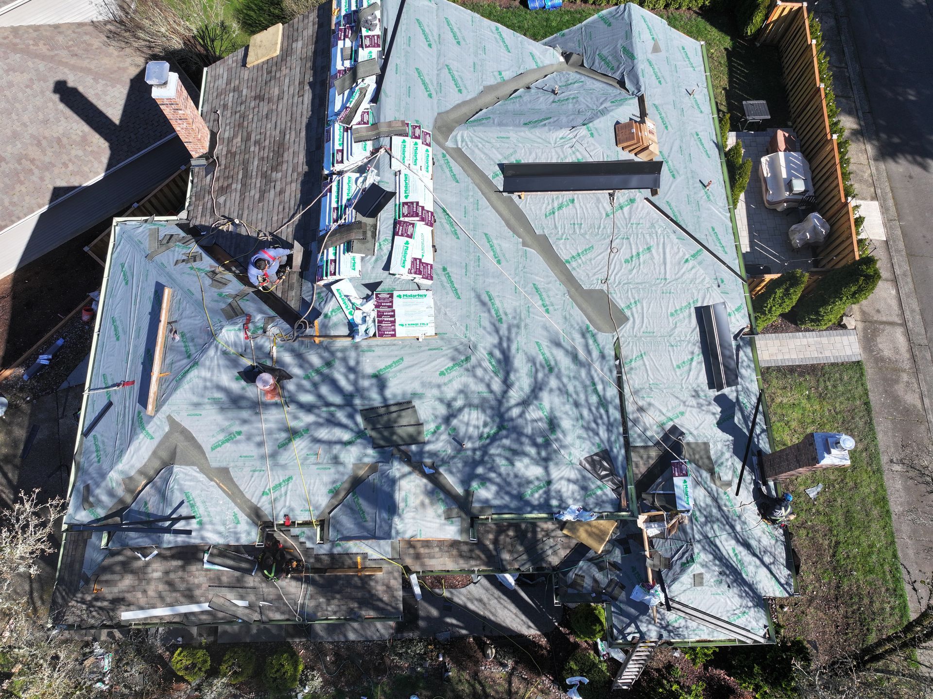 An aerial view of a house under construction with a roof being installed.