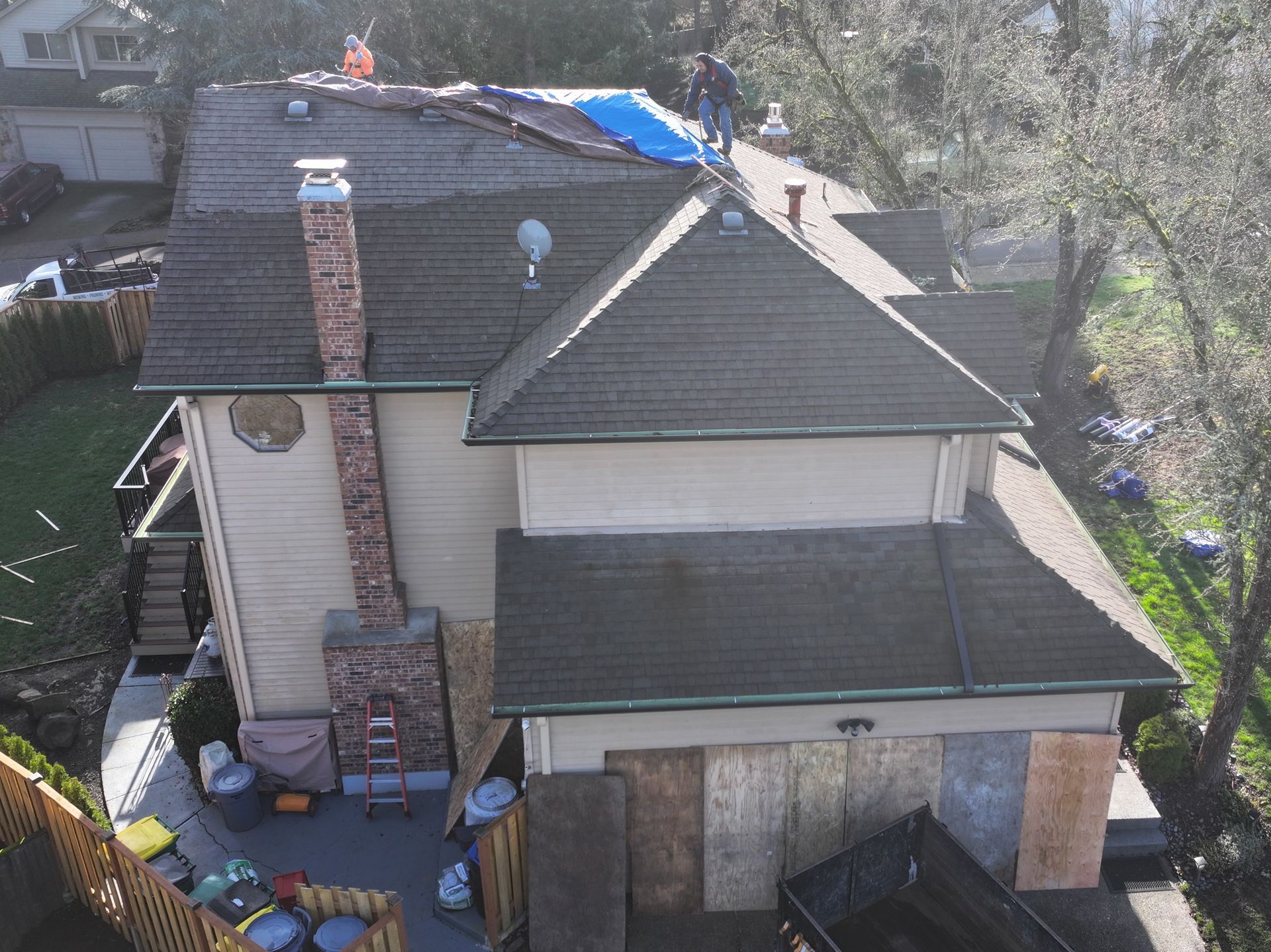 An aerial view of a house with a blue tarp on the roof