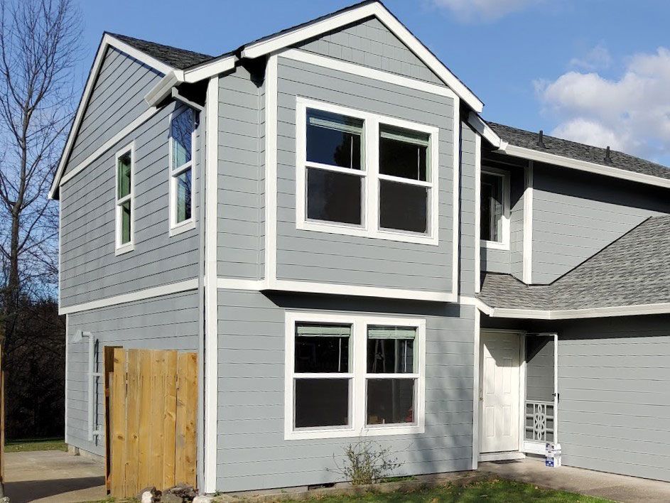 A gray house with a wooden fence in front of it