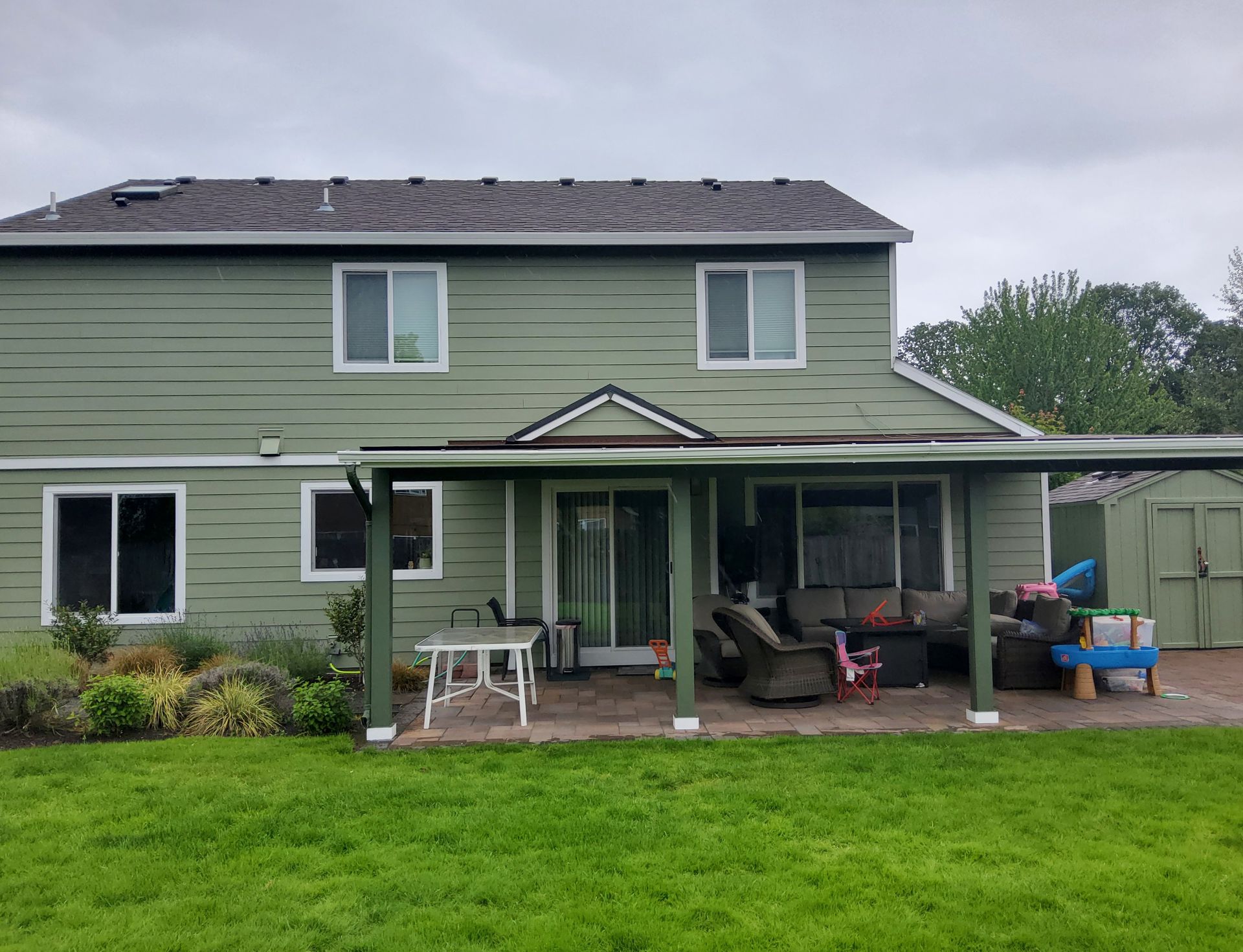 A green house with a patio and a covered porch