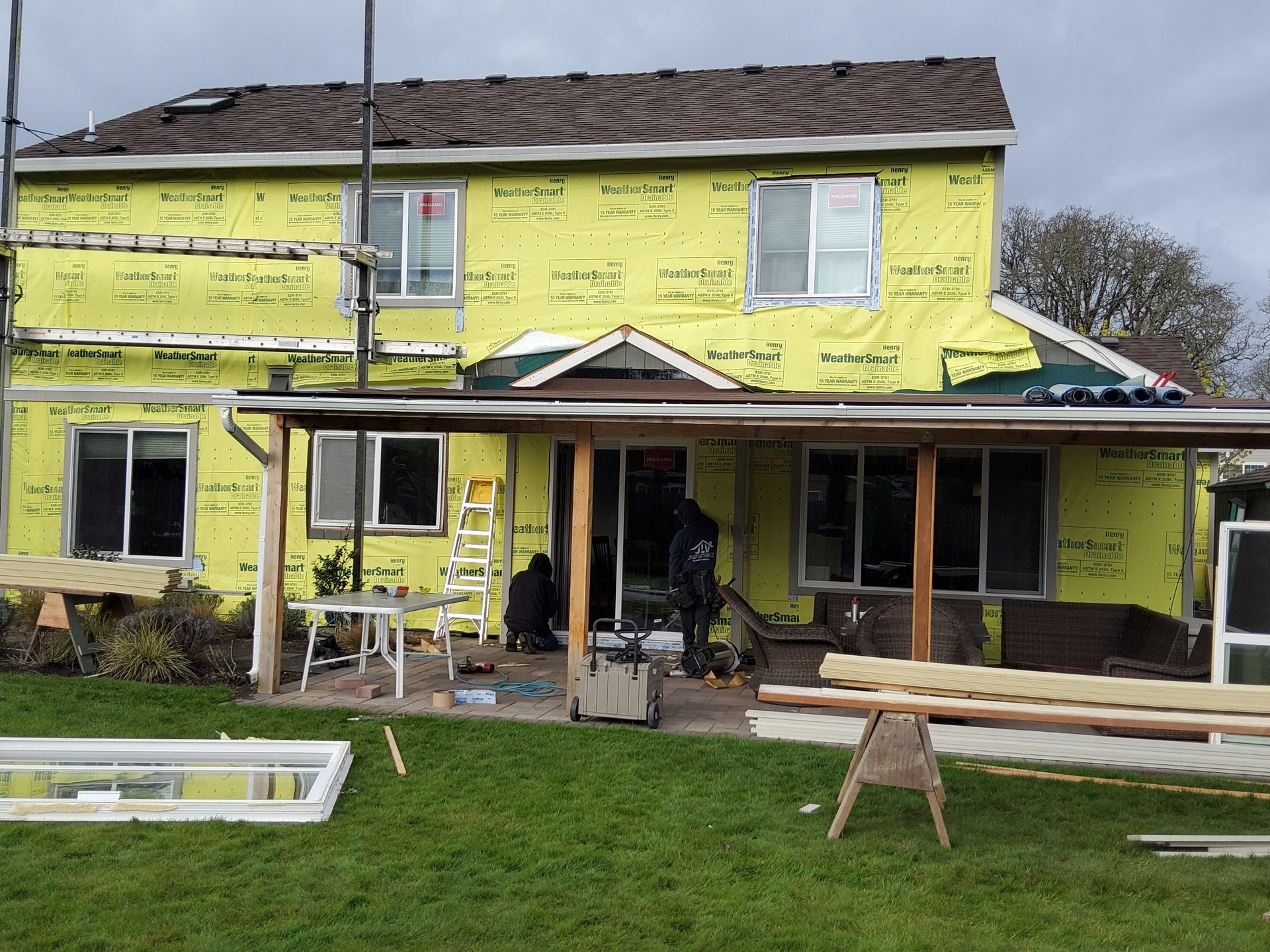 A house is being remodeled with yellow insulation and a porch