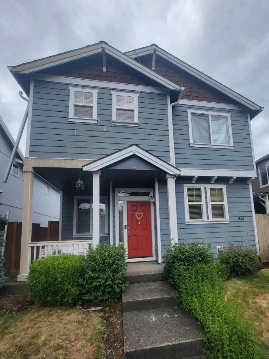 A blue house with a red door and stairs in front of it