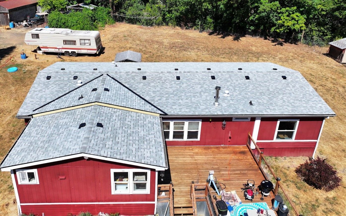 House with a deck and a trailer in the background