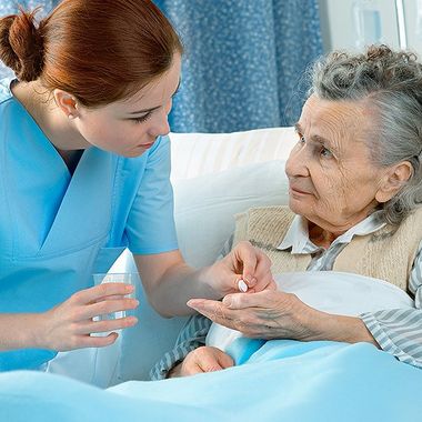 Caregiver giving the senior woman her medicine