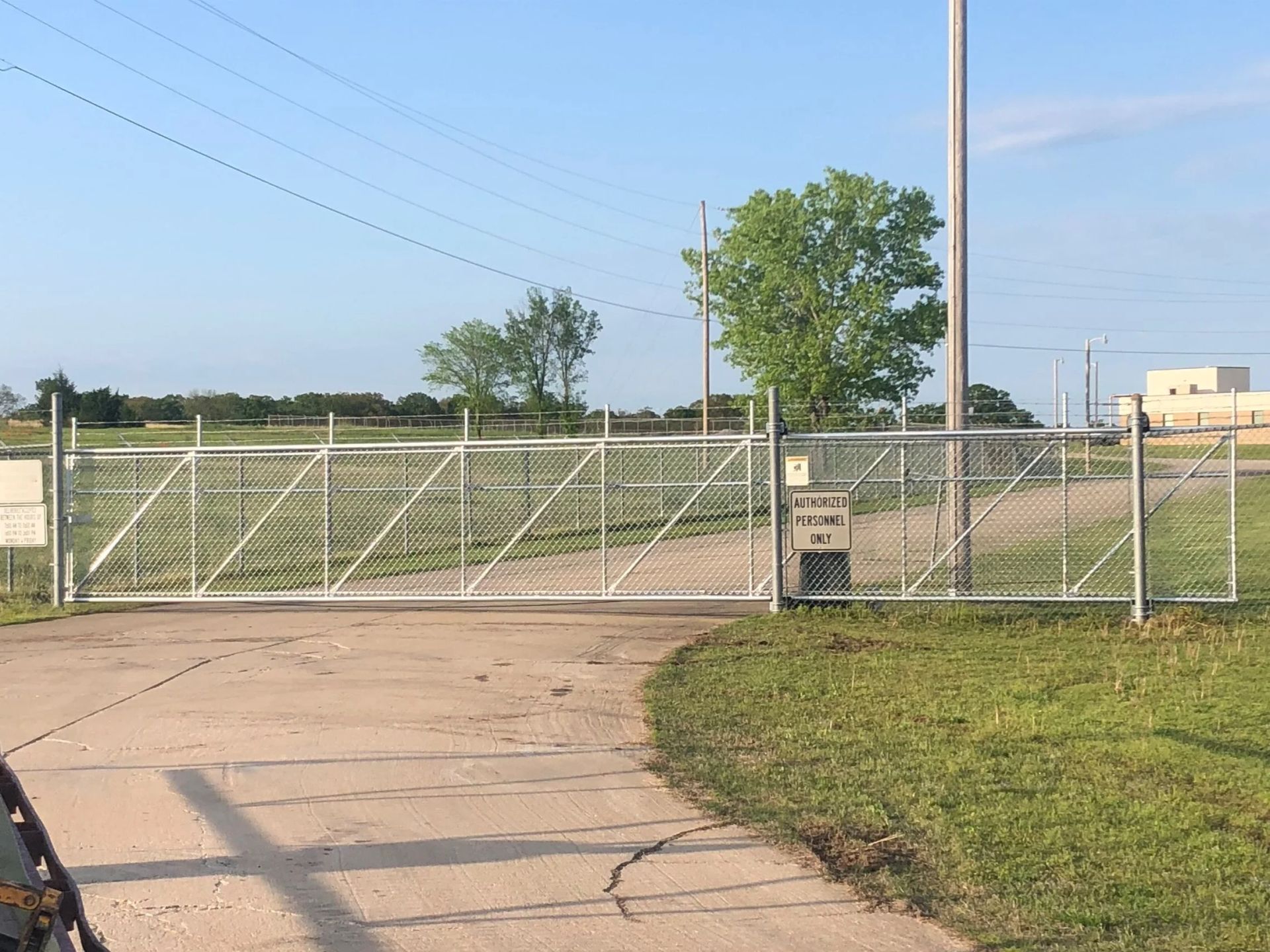 Closed chain-link gate by a grassy field under a clear blue sky
