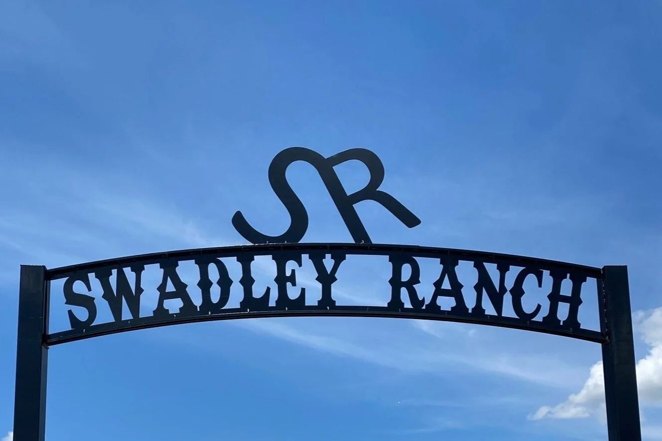 Black ranch entrance sign reading 