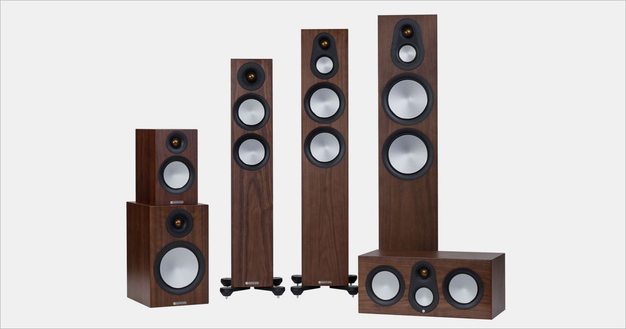 A speaker system in a studio setting. Various sizes of brown speakers with silver cones against a white backdrop.