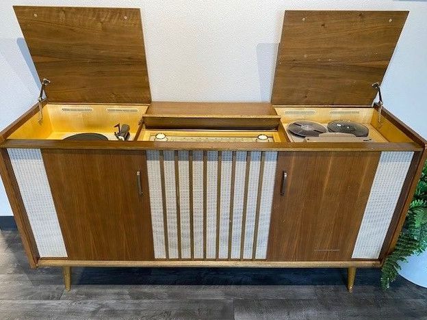 Mid-century modern stereo console featuring open lids, a turntable, a radio dial, and speakers.