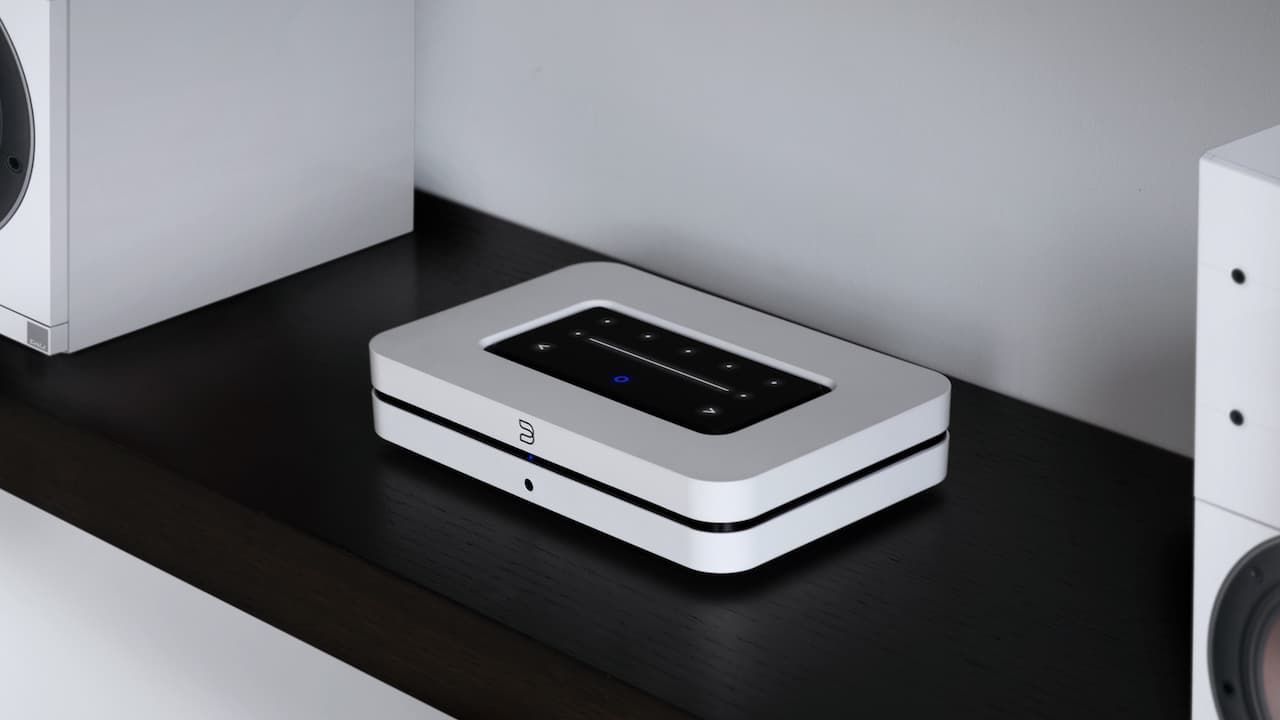 A white box is sitting on a black shelf next to two speakers.