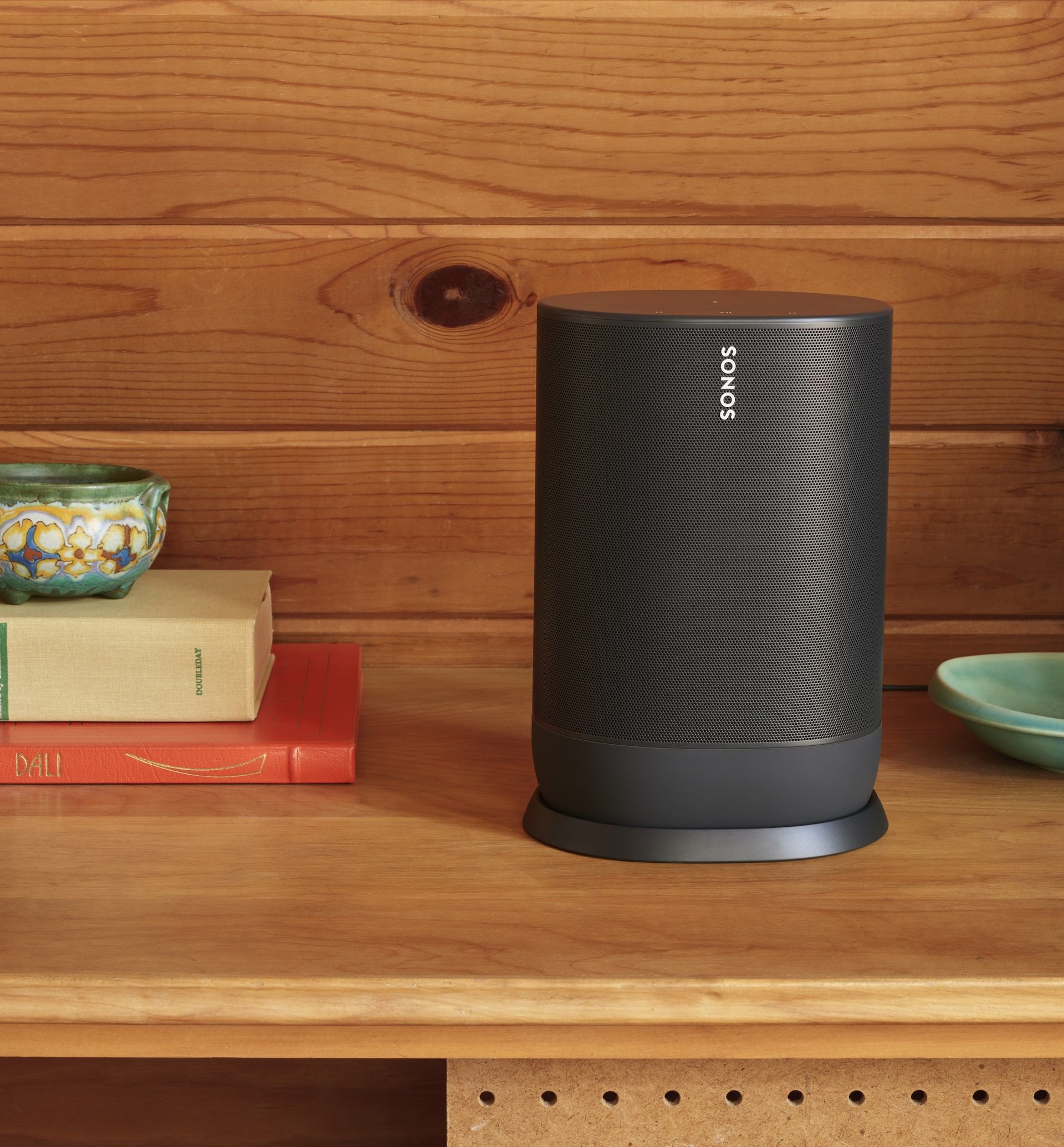 A sonos speaker is sitting on top of a wooden shelf.