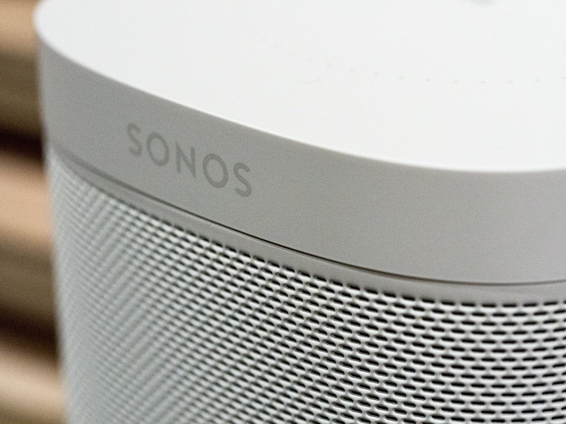 A sonos speaker is sitting on a wooden table.