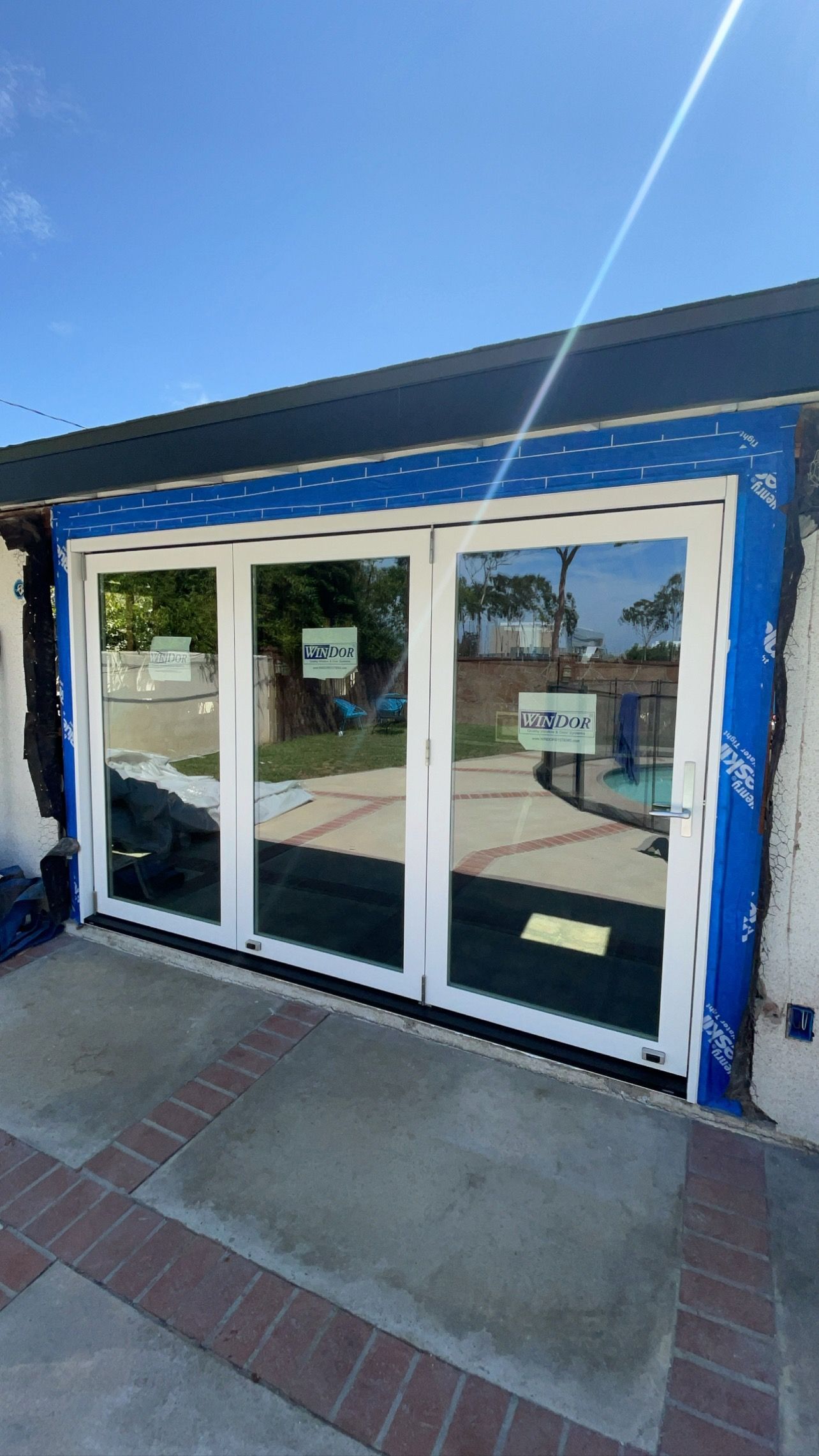 A house with a lot of windows and a pool in the background.