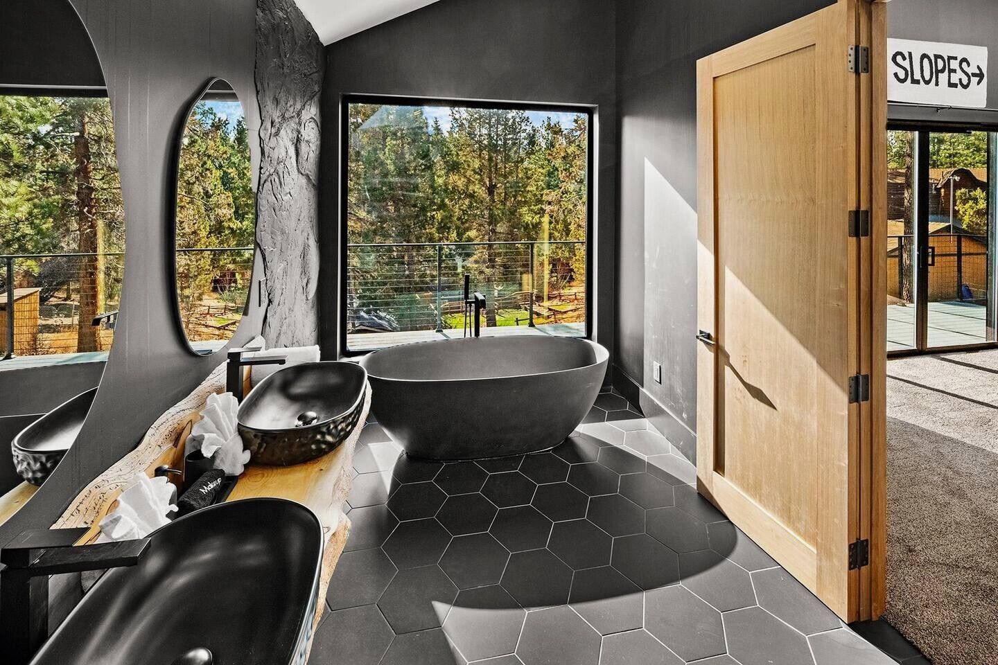 A bathroom with two sinks , a bathtub and a large window.