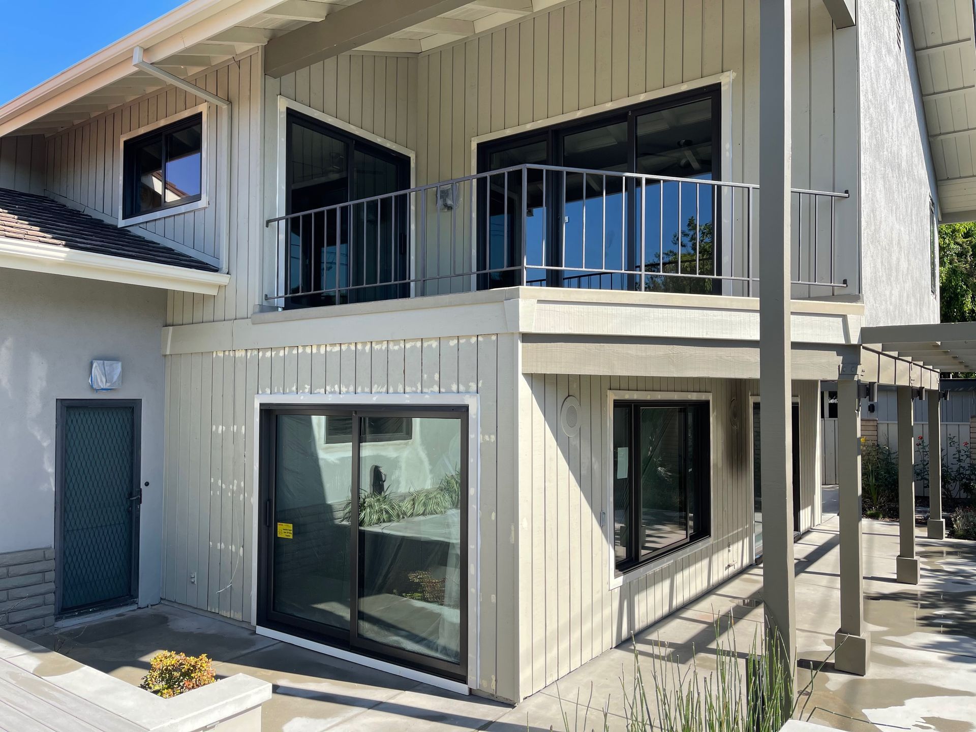 A large white house with a balcony and sliding glass doors.