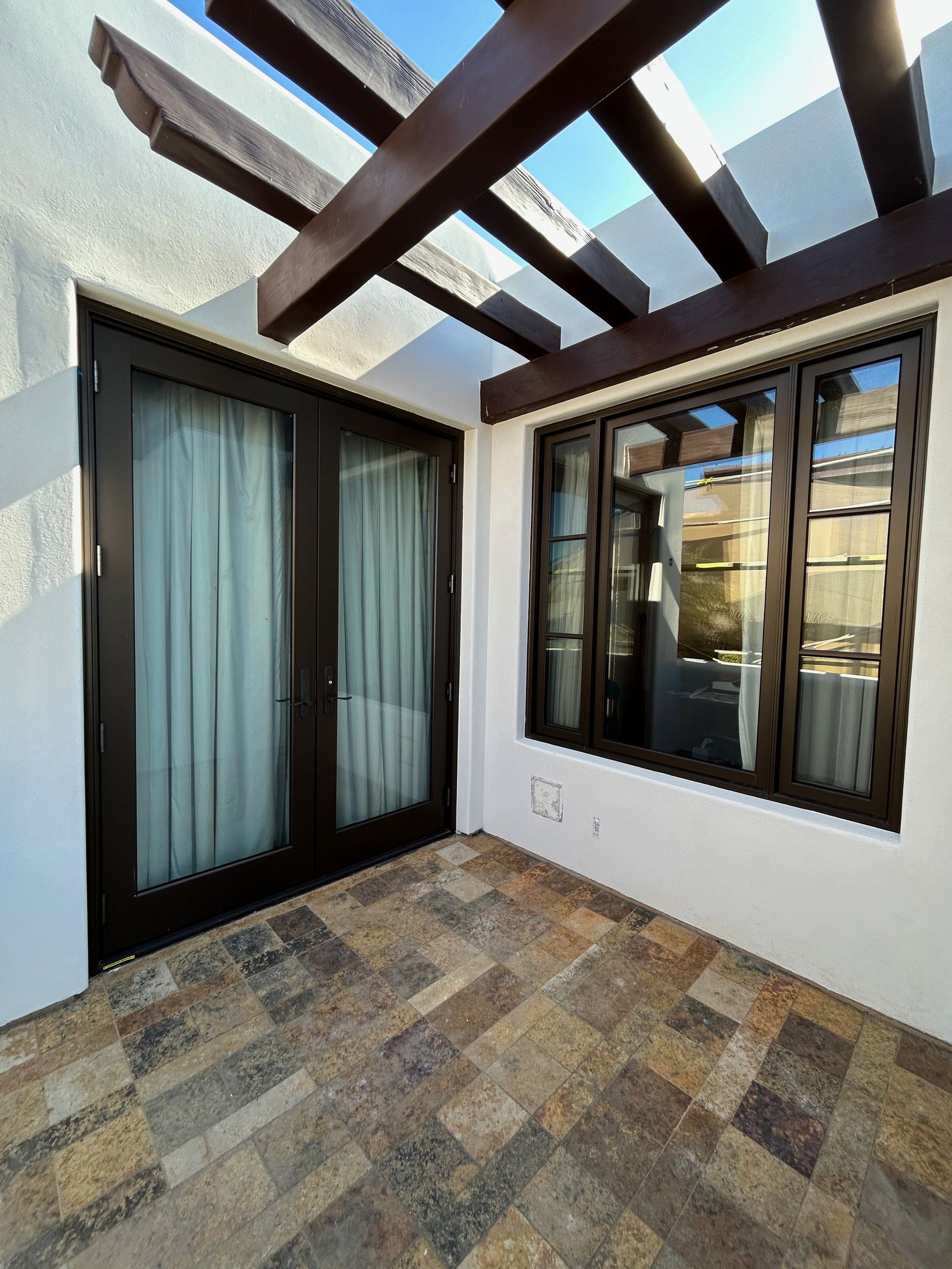 A patio with a pergola and sliding glass doors