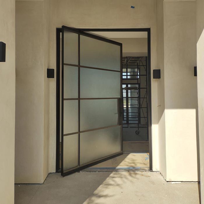A sliding glass door with a black frame is open in a hallway.