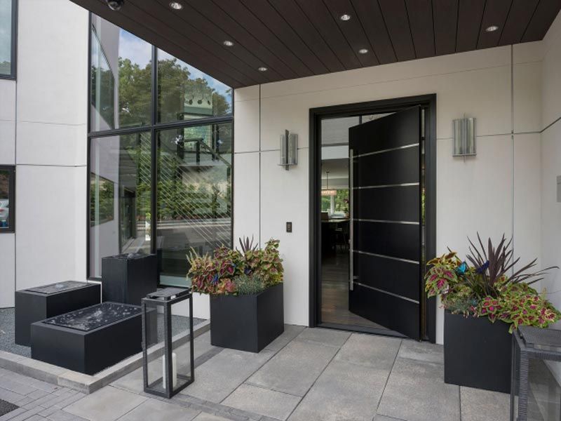 A modern house with a black door and planters in front of it