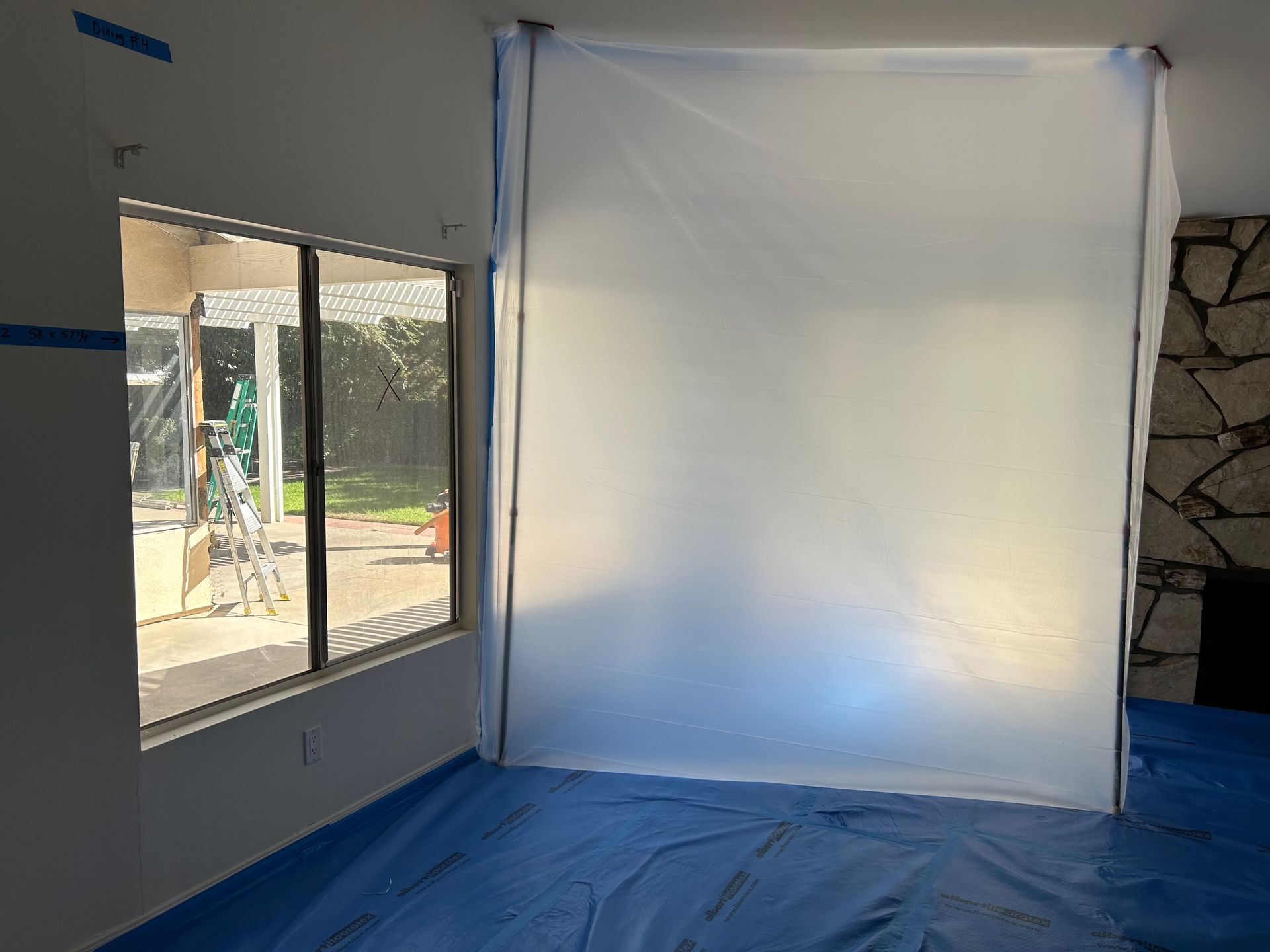 A room with a blue tarp on the floor and a white tarp on the wall.