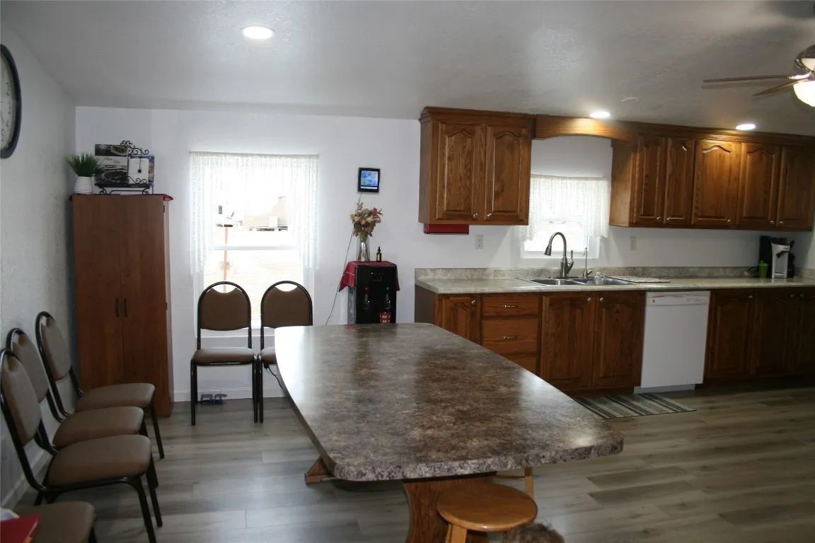 A kitchen and dining area with a stone-top table, brown chairs, and wooden cabinets.