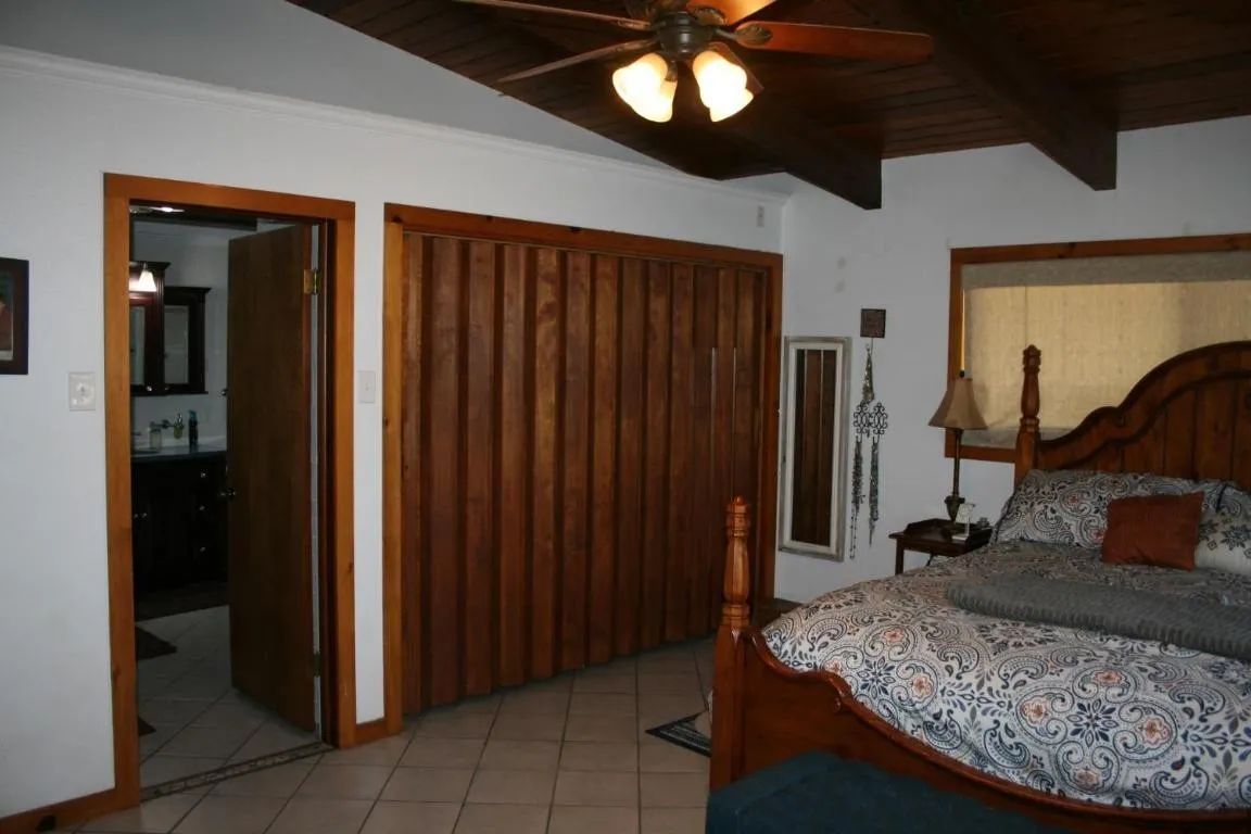 Bedroom with a wooden bed, patterned bedding, paneled closet, and doorway leading to a bathroom.