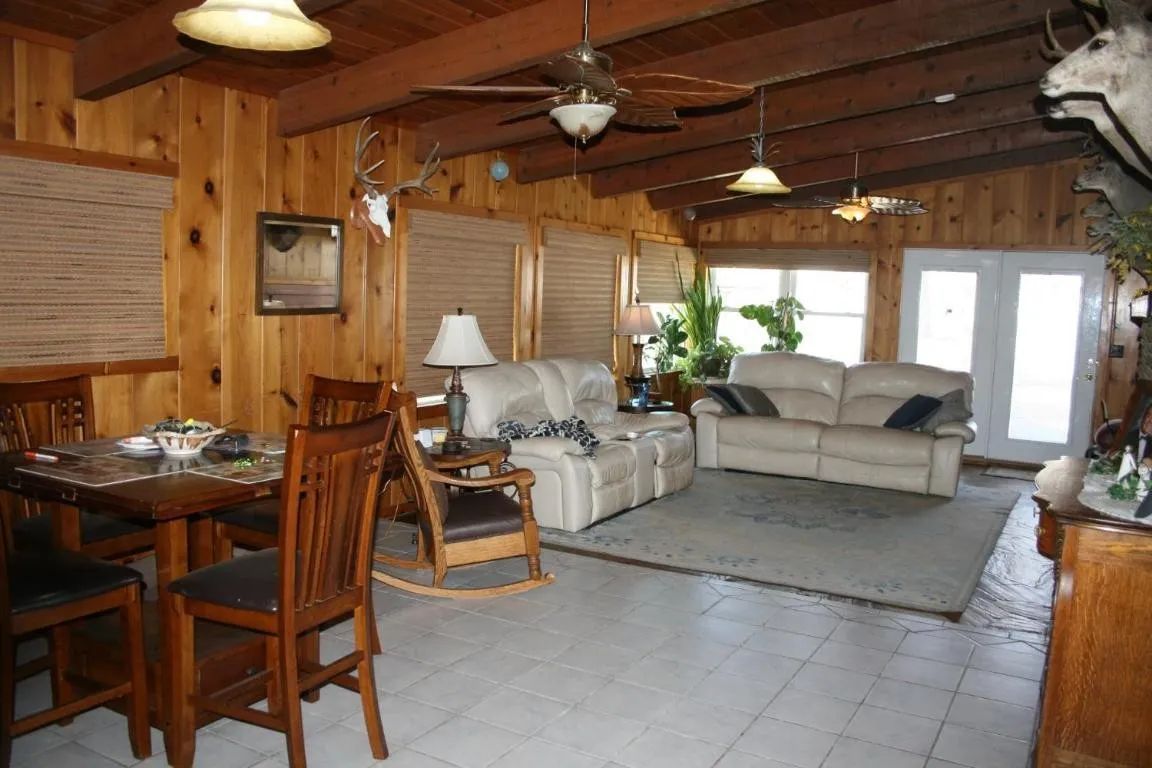 A narrow kitchen with white cabinets, blue countertops, a white sink with a tall faucet, and a window with dark curtains.