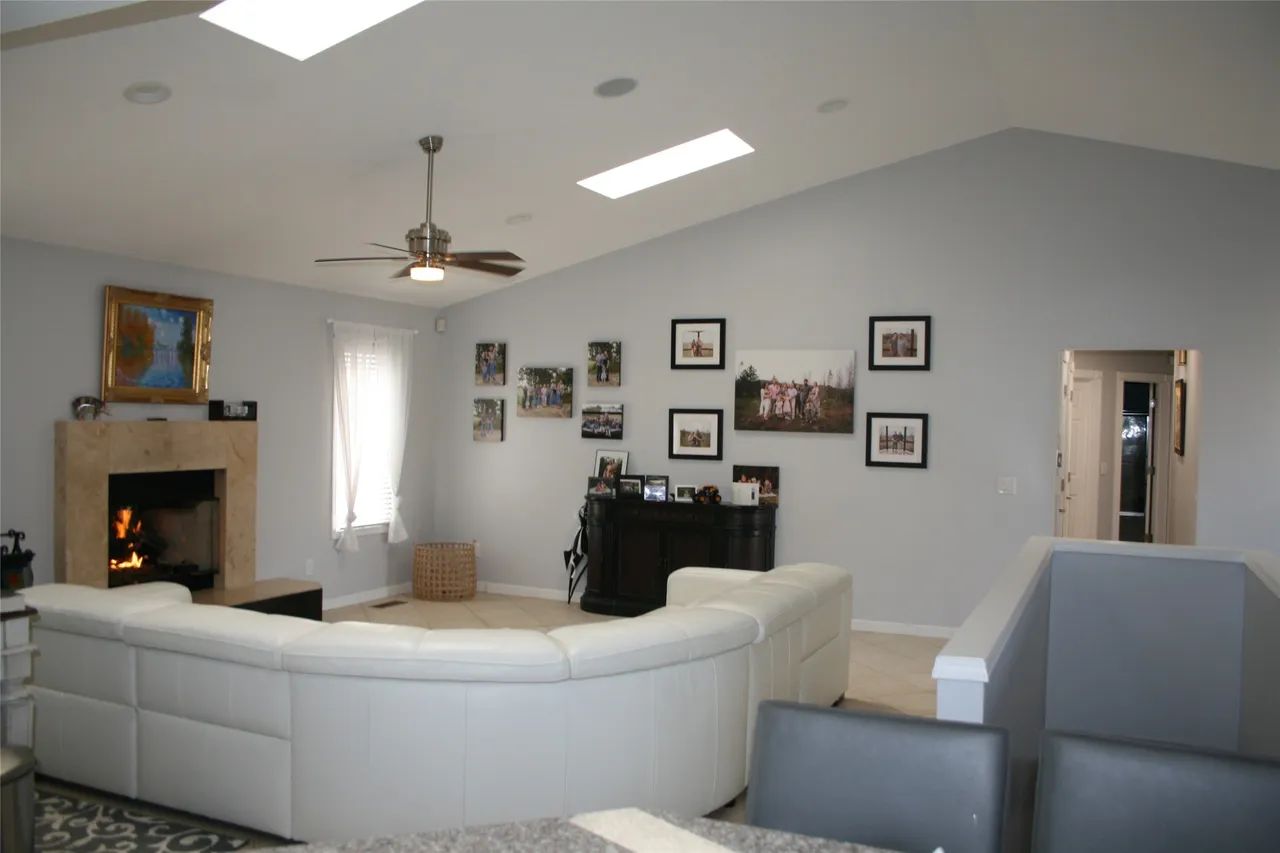 Spacious living room with a white sectional sofa, fireplace, and a gallery wall of framed photos under vaulted ceilings.