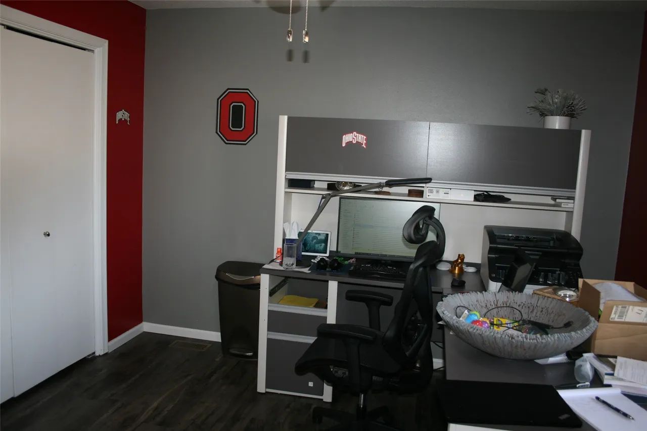 A grey office with a desk, computer monitor, office chair, and an Ohio State University logo on the wall.