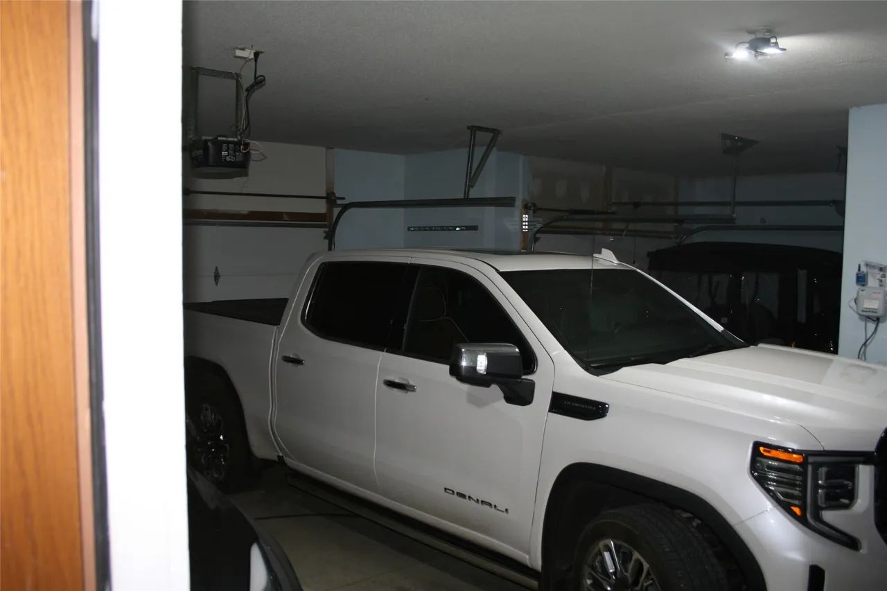 A white GMC Denali pickup truck parked inside a home garage.