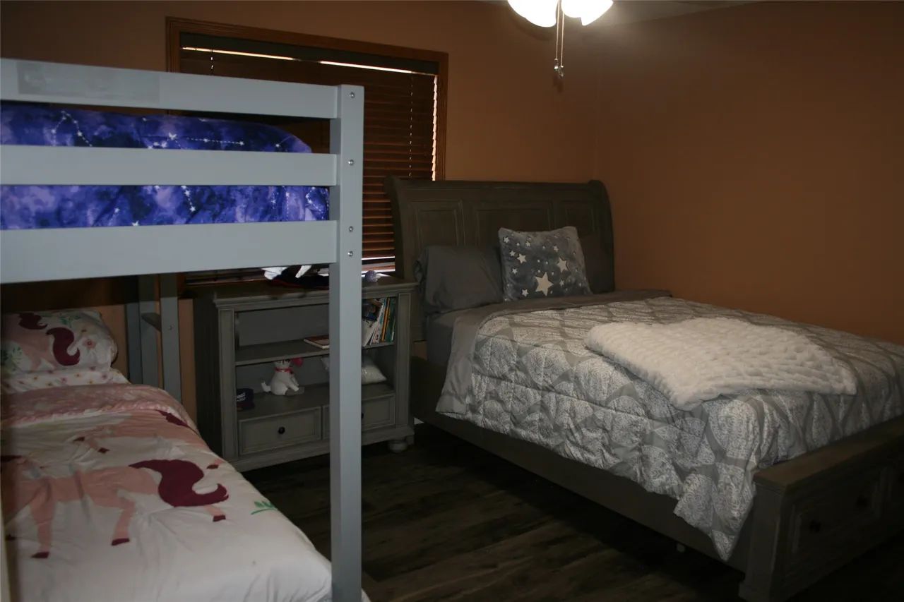 A child's bedroom featuring a gray bunk bed with unicorn bedding, a gray dresser, and a full-sized bed with gray linens.