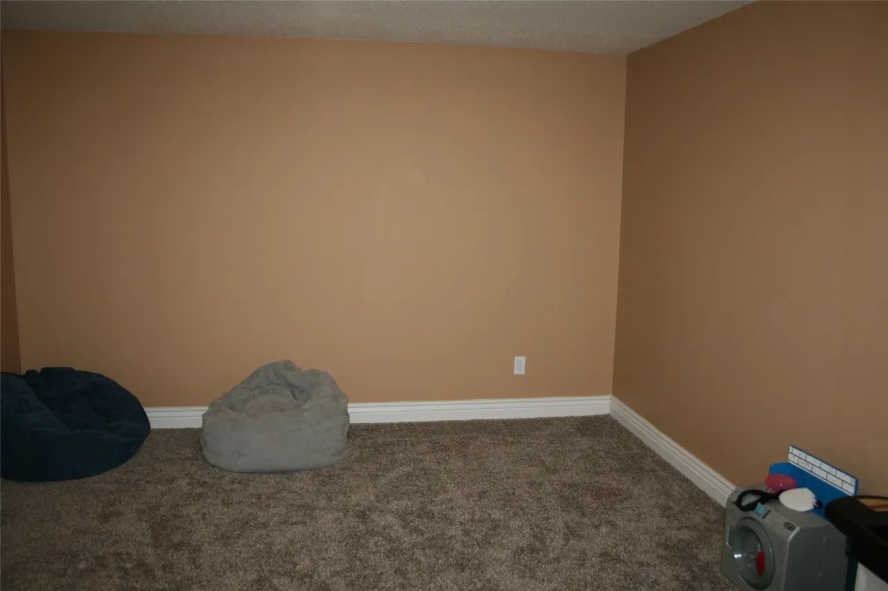 A room with tan walls, carpeted floor, two beanbag chairs, and an air purifier in the corner.