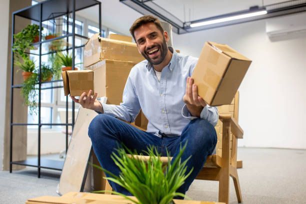 A man in a white suit is painting a room, preparing it for an office move.