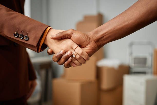  Two individuals in an office shaking hands, symbolizing a collaboration with Apartment Moving Solu