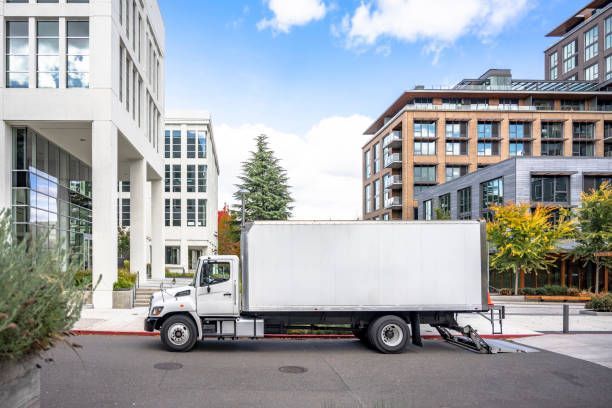 A man and woman load boxes into a moving truck, representing a moving company in action.