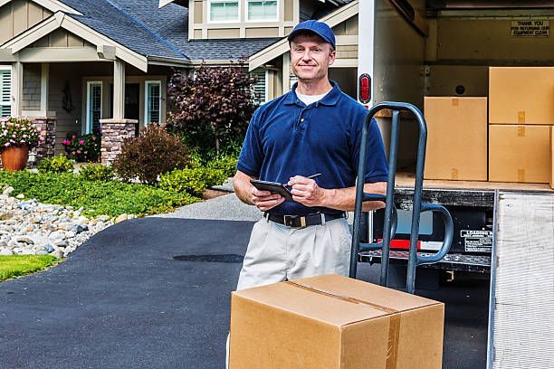  A man stands beside a moving truck filled with boxes, representing licensed moving services in Lake