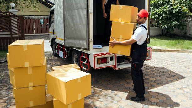 . Three people are moving boxes into a room, illustrating the efforts of a local moving company.