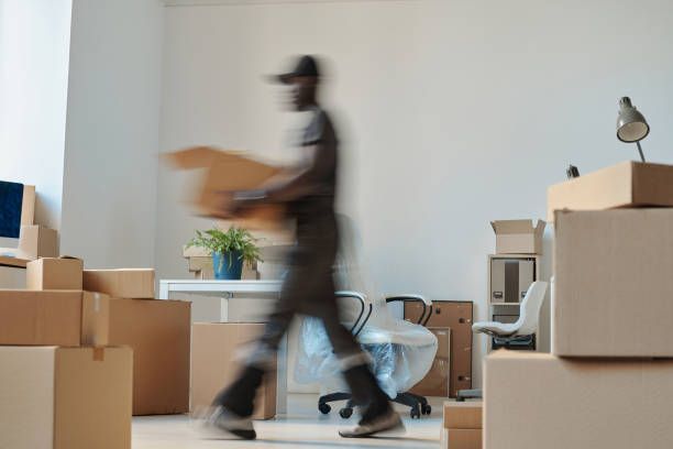 An office scene shows a man carrying boxes, part of Apartment Moving Solutions' services.