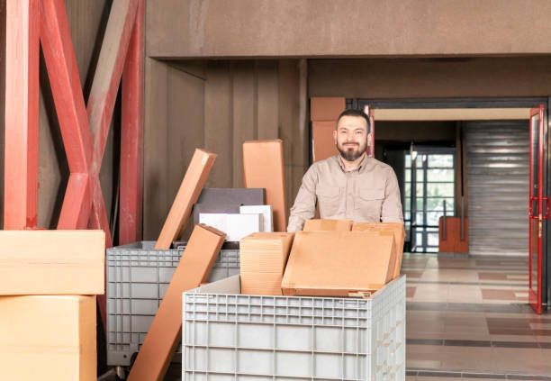 A man is moving boxes in an office setting for Apartment Moving Solutions.