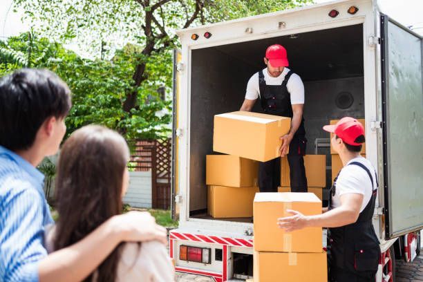A white delivery truck, marked with a moving company logo, drives on the road, indicating its purpose of relocation.