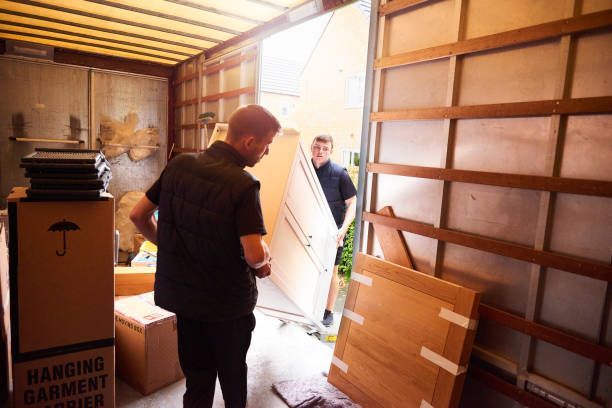 wo men in blue shirts are carefully Packing and Moving a large piece of furniture during a flood damage restoration process.