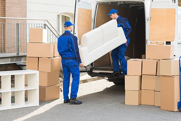 Two men are carrying furniture from a moving truck marked
