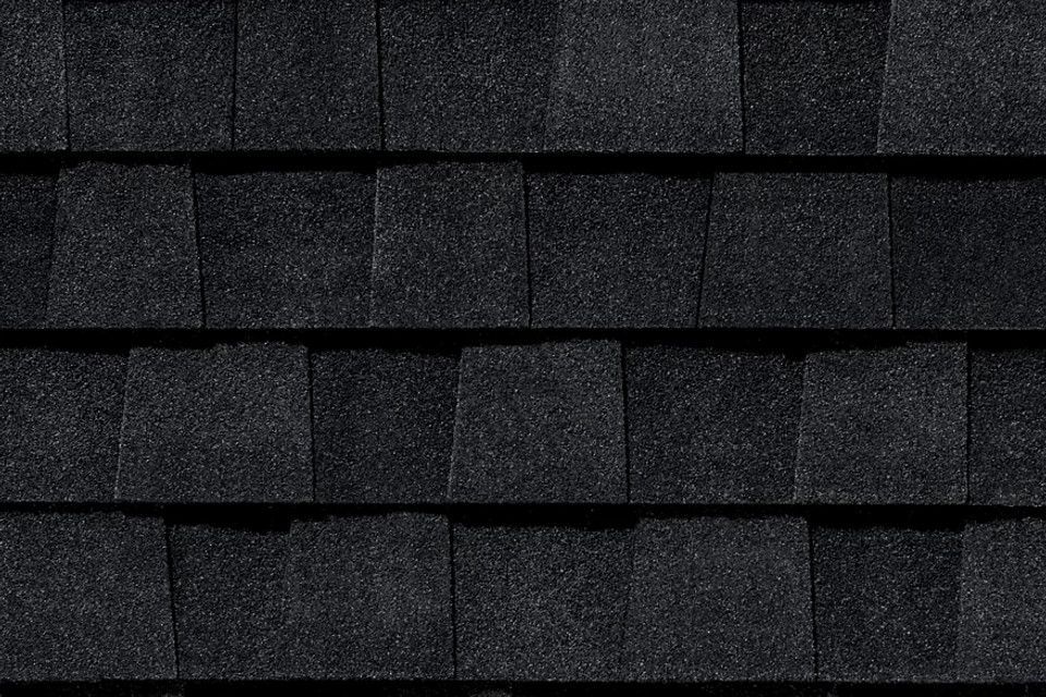 A close up of a row of black shingles on a roof.