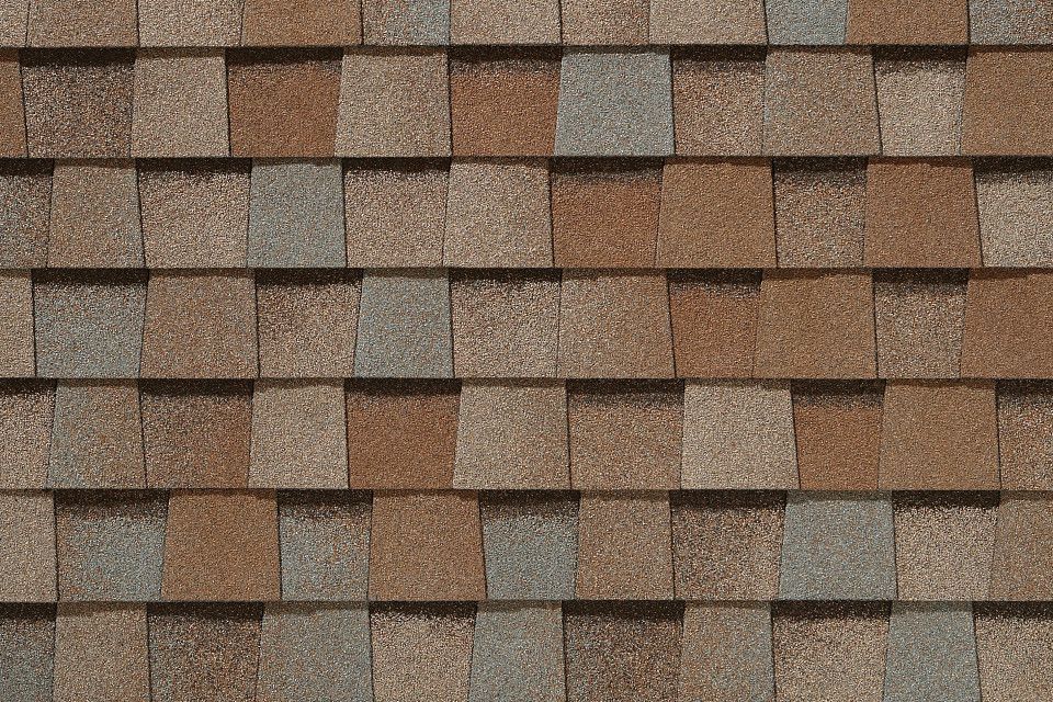 A close up of a roof with brown and gray shingles.
