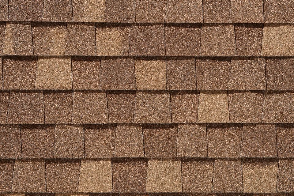 A close up of a roof with brown shingles.