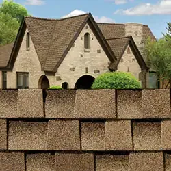 Brown asphalt shingles on a house with light-colored stone facade, arched entryway, and gabled roof.