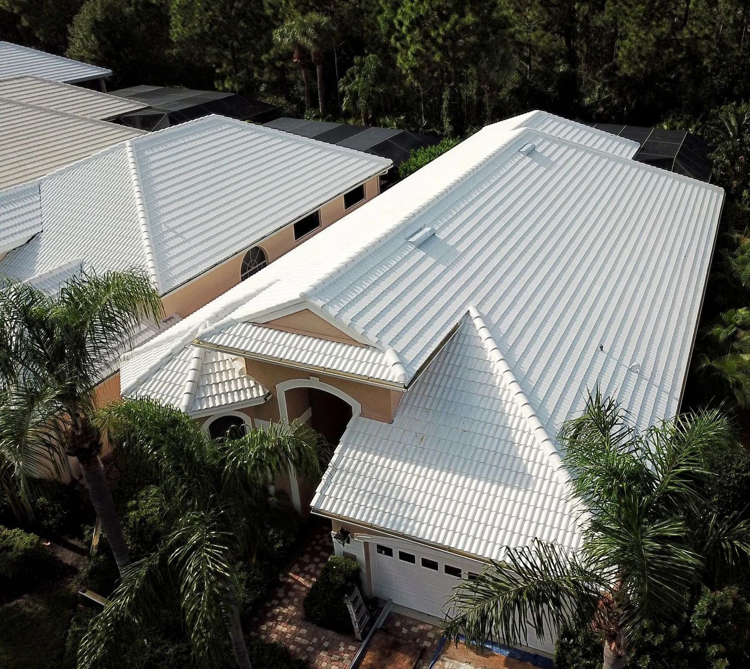 an aerial view of a house with a white roof surrounded by trees.