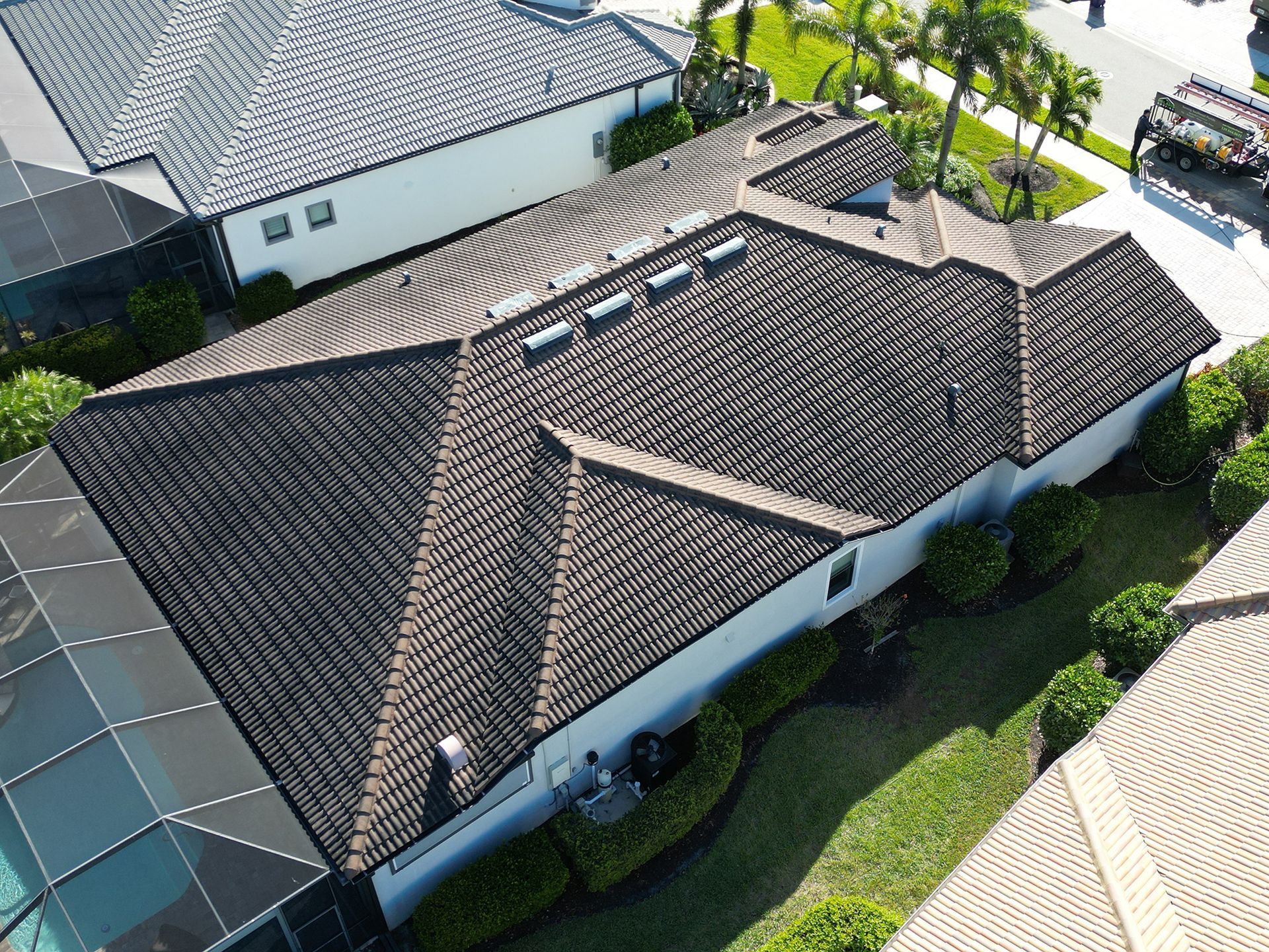 Aerial view of a house with a tiled roof and white walls in a suburban neighborhood.