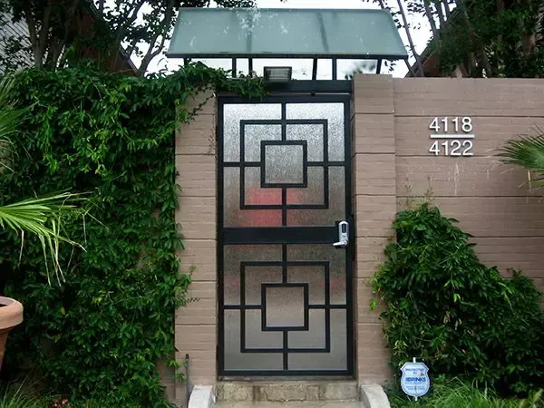 Black gate with geometric design, frosted glass, beige wall, ivy, address 4118 and 4122.