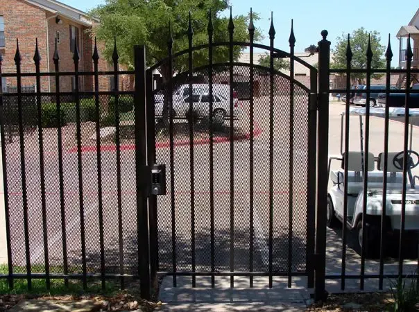 Black metal gate with matching fence, enclosing a parking area. A golf cart is visible to the right.